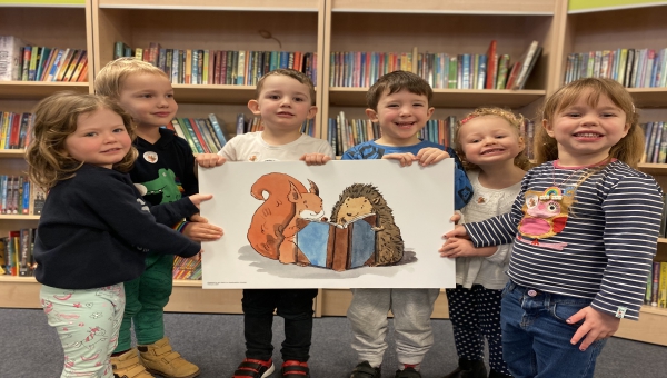 Children from Bargates Nursery hold up a Squirrel Club library card