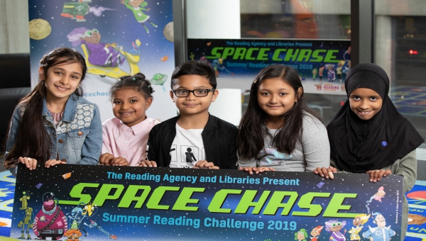 Five children holding a banner saying 'Space Chase' summer reading challenge 2019