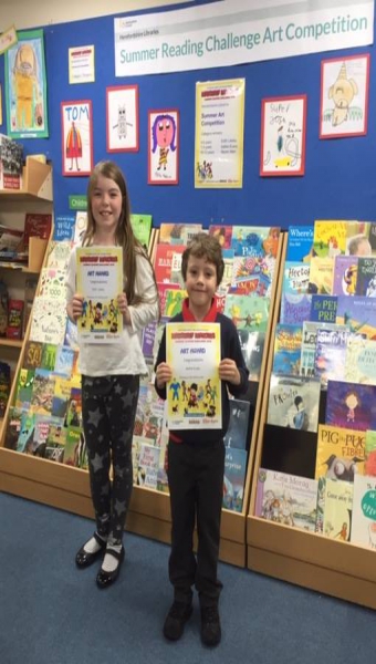 A girl and boy holding a certificate for winning the Summer Reading Challenge 2018 art competition