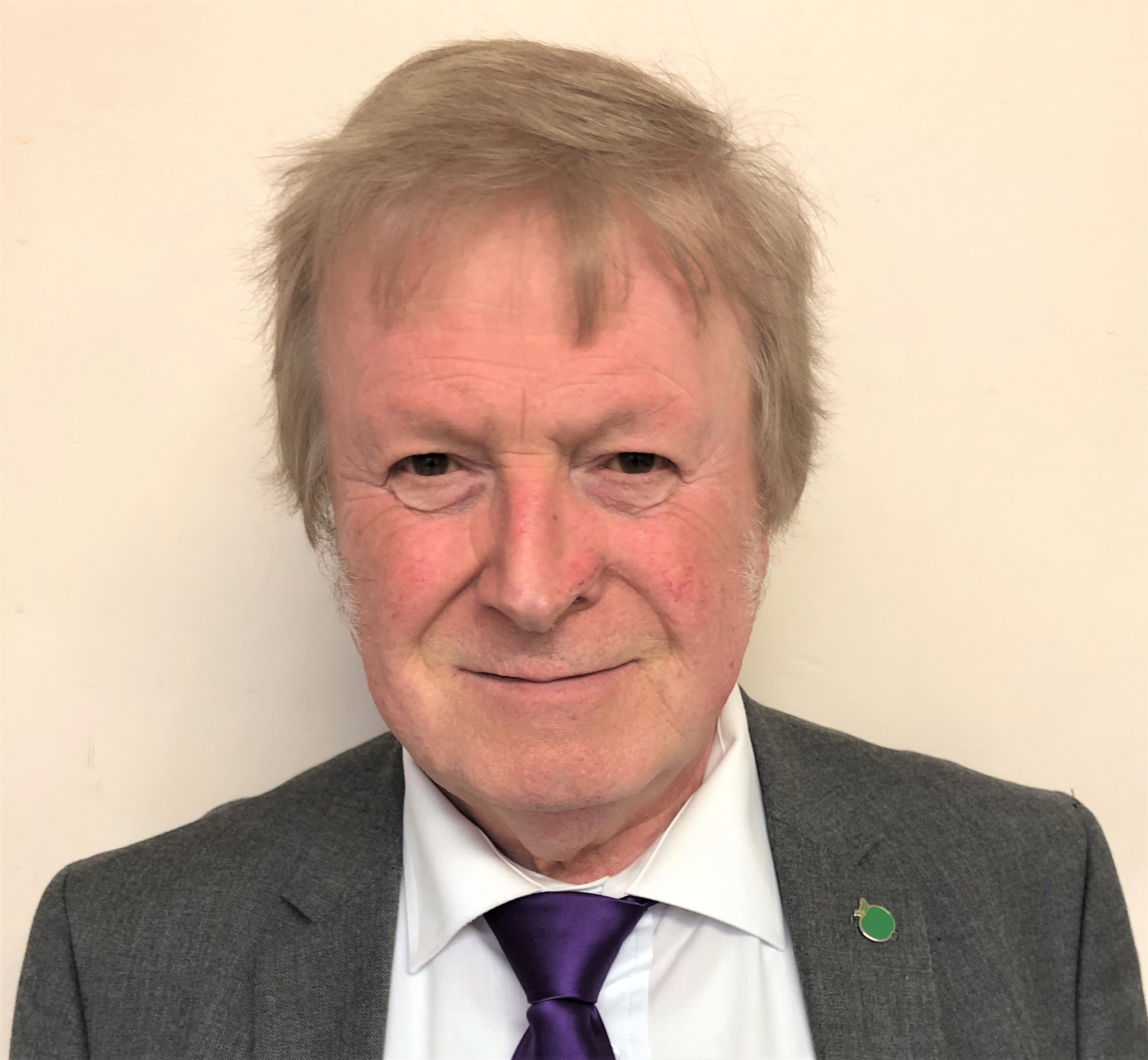 Portrait of Councillor Bernard Hunt wearing a suit and tie against a cream background