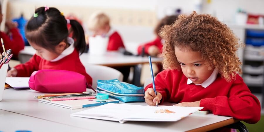 Two girls sitting writing at school