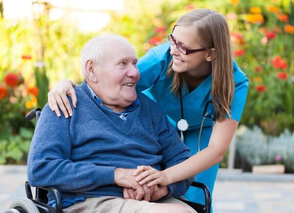 Elderly man in wheelchair with carer