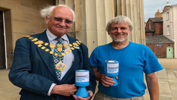 Chairman of Herefordshire Council stood next to Parkinsons UK Hereford and District Chairman, both holding collection tins