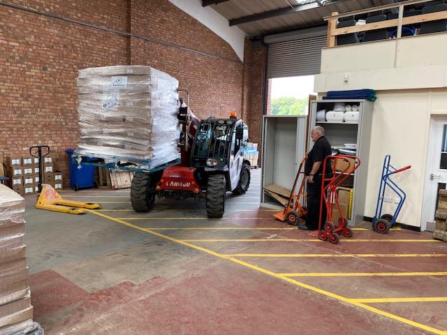 forklift truck loading boxes of PPE onto a lorry