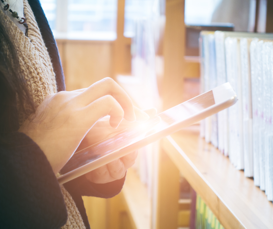 Hand typing on tablet in library