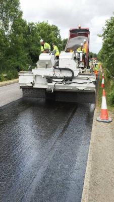 Machine surface dressing a road with bitumen