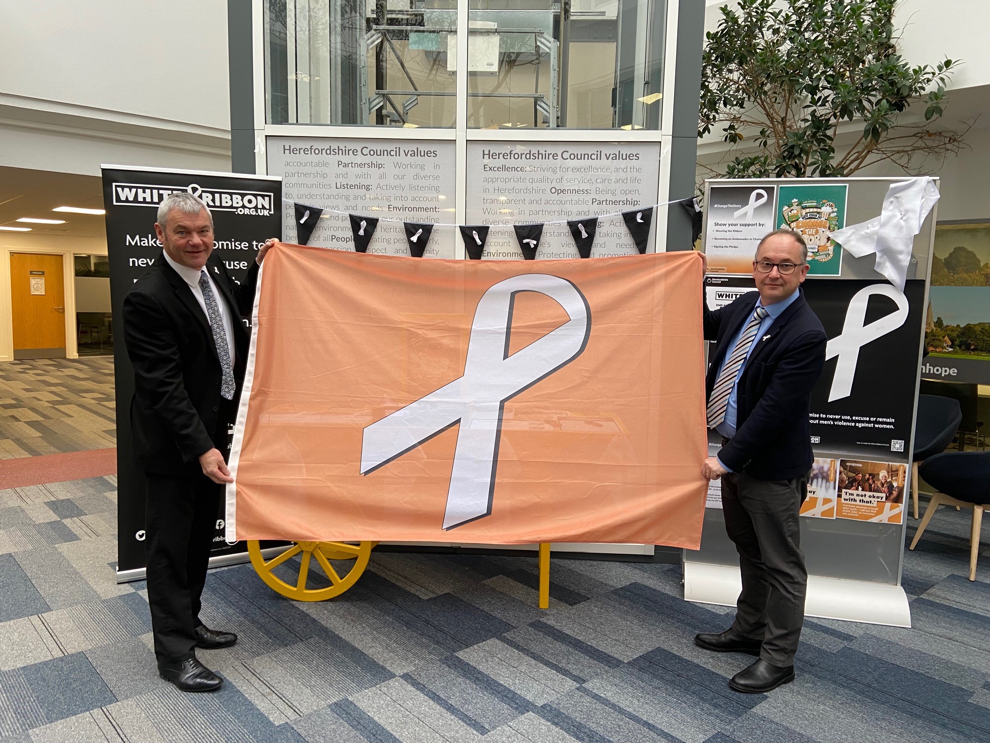 Paul Walker and Cllr Jonathan Lester holding a white ribbon flag