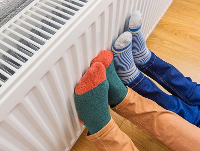 Two pairs of feet resting on a radiator