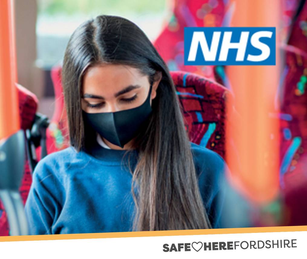young female with dark hair, sitting on a bus wearing a face mask -with text Safe Herefordshire