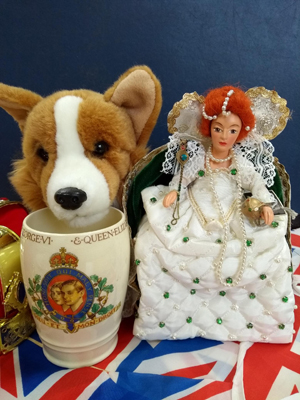 Collection of royal memorabilia including toy corgi, coronation mug, doll dressed as Queen Victoria